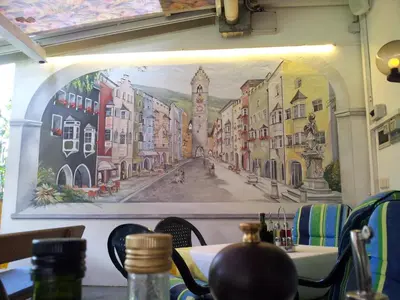 a painting on the wall of a restaurant with a table at Hotel Hubertushof in Vipiteno