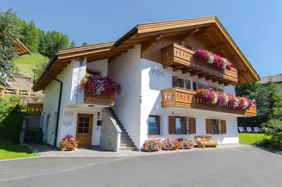 a building with flower boxes and balconies on it at Appartamenti Vilin in San Cassiano