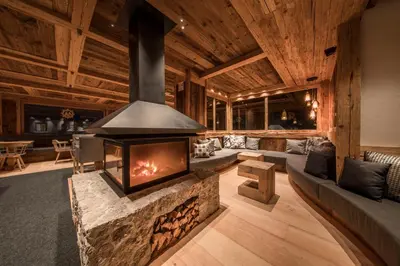 a living room with a fireplace in a log house at Rifugio Salei in Canazei