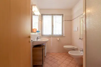 a bathroom with a sink and a toilet and a window at Appartamenti Le Plejadi in Cavalese