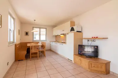 a kitchen and living room with a tv and a table at Appartamenti Le Plejadi in Cavalese
