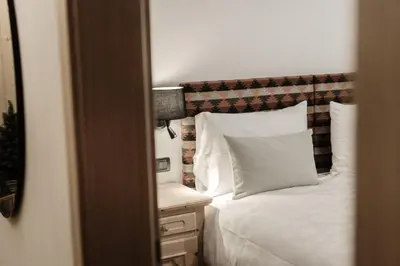 a bedroom with a white bed and a night stand with a lamp at Residence Telemark in Santa Cristina in Val Gardena