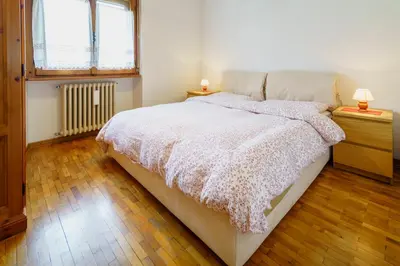 a bedroom with a bed and two night stands with lamps at Villa Ca Perosego - Stayincortina in Cortina dʼAmpezzo