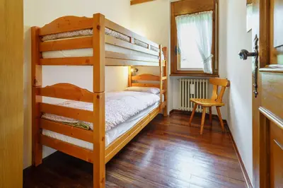 a bedroom with two bunk beds and a chair at Villa Ca Perosego - Stayincortina in Cortina dʼAmpezzo