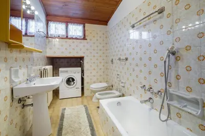 a bathroom with a sink toilet and a washing machine at Villa Ca Perosego - Stayincortina in Cortina dʼAmpezzo