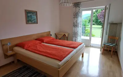 a bedroom with a bed with red sheets and a window at Haus Klavenz in Caldaro
