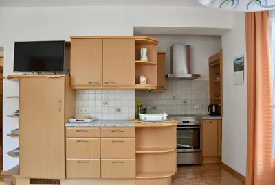 a kitchen with wooden cabinets and a flat screen tv at Haus Klavenz in Caldaro