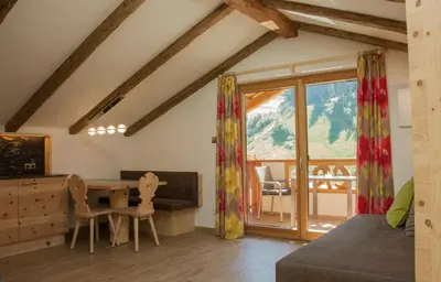 a living room with a vaulted ceiling and a couch at Apartments Edera in Selva di Val Gardena