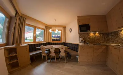 a kitchen with wooden cabinets and a table and a sink at Apartments Edera in Selva di Val Gardena