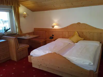 a bedroom with a large wooden bed and a desk at Garni Waltoy in Selva di Val Gardena