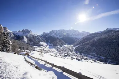 a view of a snowy mountain with the sun in the sky at Garni Waltoy in Selva di Val Gardena