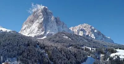 a snow covered mountain with a lake in front of it at Garni Waltoy in Selva di Val Gardena