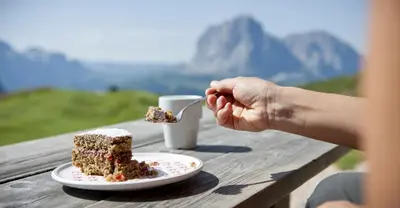 a person eating a piece of cake on a table at Garni Waltoy in Selva di Val Gardena