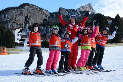 a group of children standing on skis in the snow at Garni Waltoy in Selva di Val Gardena