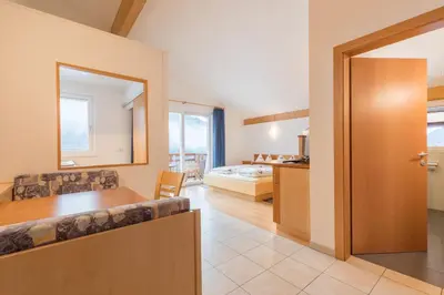 a living room with a table and a bedroom at Appartements Haus Pichler in Eggen