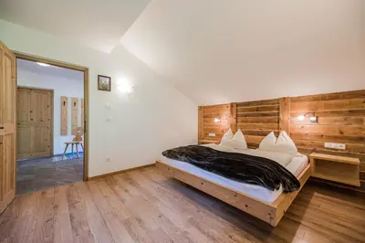 a bedroom with a large bed with a wooden wall at Haubenthal in Villabassa