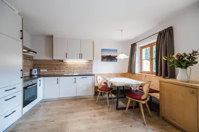 a kitchen with white cabinets and a table and chairs at Haubenthal in Villabassa