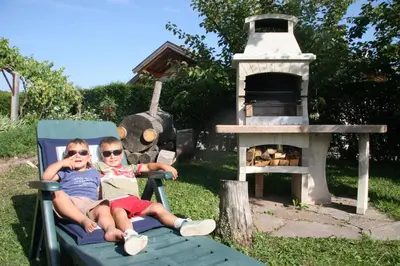 two children sitting on a lawn chair in front of a grill at Schötzerhof in Meltina
