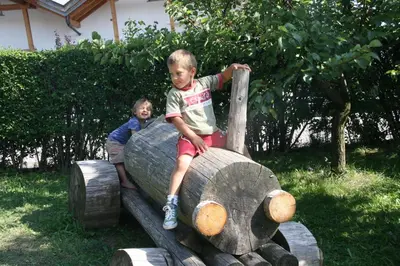 two young boys sitting on top of a wooden log at Schötzerhof in Meltina
