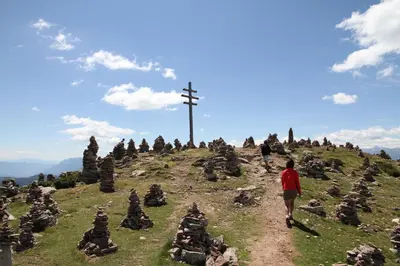 a man walking up a hill with a cross on top at Schötzerhof in Meltina