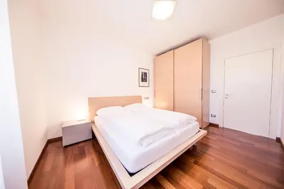 a bedroom with a white bed and a wooden floor at Josefshof in Caldaro