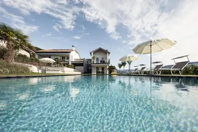 a swimming pool with an umbrella and a house at Josefshof in Caldaro