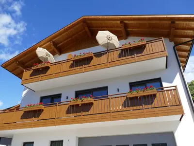 a building with a wooden balcony with flowers on it at Haller Hof in Tirolo