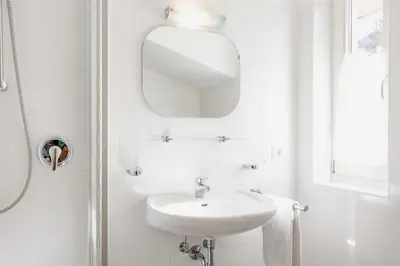 a white bathroom with a sink and a mirror at Appartements Beikircher in Valdaora
