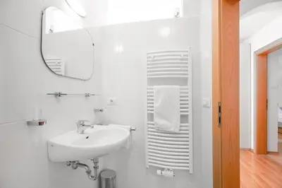 a white bathroom with a sink and a mirror at Appartements Beikircher in Valdaora
