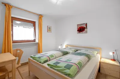 a bedroom with a bed and a table and a window at Appartements Beikircher in Valdaora