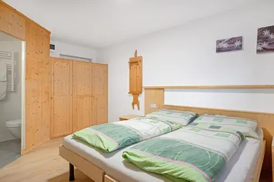 a bedroom with a bed with green and white pillows at Appartements Beikircher in Valdaora