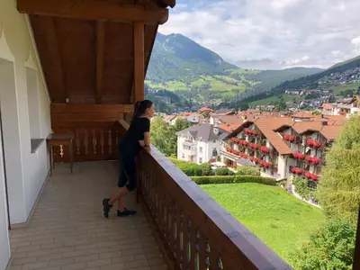 a woman standing on a balcony looking at a city at Appartements Else in Ortisei
