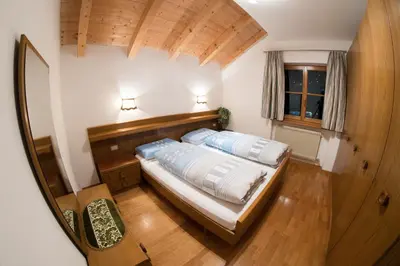 a bedroom with a bed with a wooden headboard and a window at Appartements Else in Ortisei