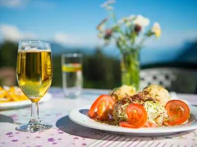 a table with a plate of food and a glass of wine at Gasthaus Gasteiger in Lagundo