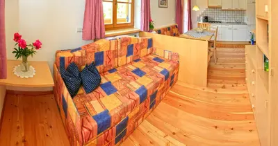 a living room with a couch and a kitchen at App Unterhoezlhof in Valdaora