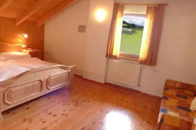 a bedroom with a bed and a large window at App Unterhoezlhof in Valdaora