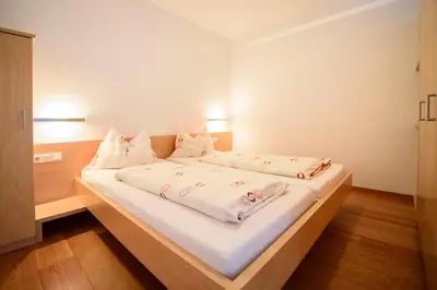 a bedroom with a large bed with white sheets and pillows at Arboris Appartement in Appiano sulla Strada del Vino