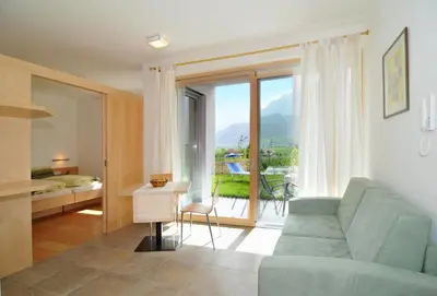 a living room with a couch and a large window at Arboris Appartement in Appiano sulla Strada del Vino