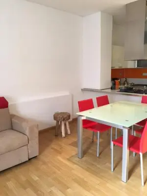 a living room with a table and red chairs at Nel Cuore Verde di Bolzano in Bolzano