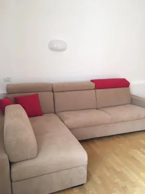 a brown couch with red pillows in a living room at Nel Cuore Verde di Bolzano in Bolzano