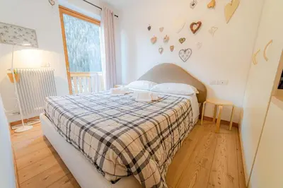 a bedroom with a bed with a plaid blanket and a window at Appartamento Lucia in Penia
