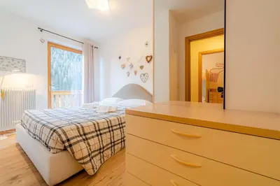 a bedroom with a bed and a dresser with a mirror at Appartamento Lucia in Penia