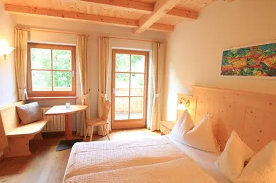 a bedroom with a bed and a table and windows at Paalhof in Castelrotto