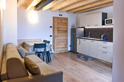a living room with a couch and a kitchen at Tilde in Tesero