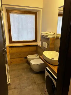 a bathroom with a toilet and a sink and a window at Tilde in Tesero