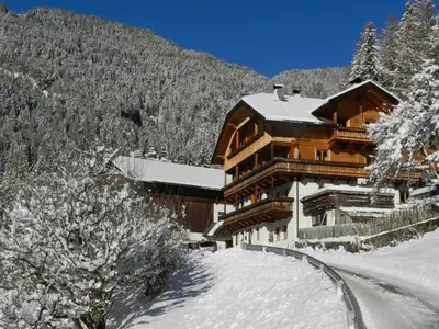 a large building in the snow next to a mountain at Gedrarzerhof in Luson