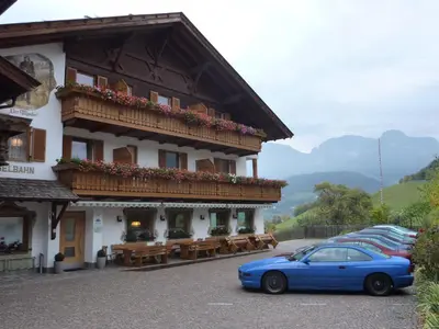 a table and chairs on a porch with a view of mountains at Gasthof Pizzeria Unterwirt in Collepietra