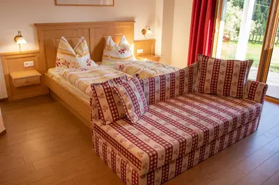a bedroom with a couch and a bed and a chair at Leitenhof in Val di Vizze