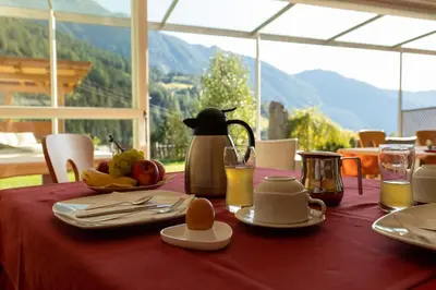 a table with a red table cloth with food and juice at Leitenhof in Val di Vizze