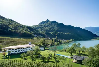 a resort with a lake and mountains in the background at Seehotel Ambach in Caldaro